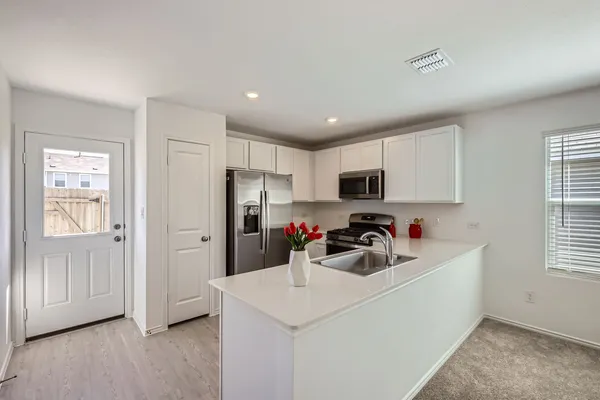 a kitchen that has a lot of cabinets a sink and appliances