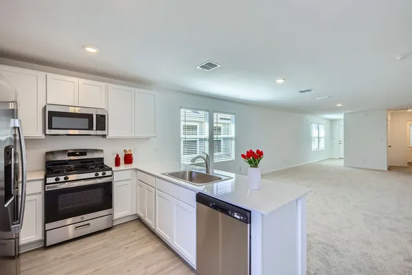 a kitchen that has a lot of white cabinets and stainless steel appliances