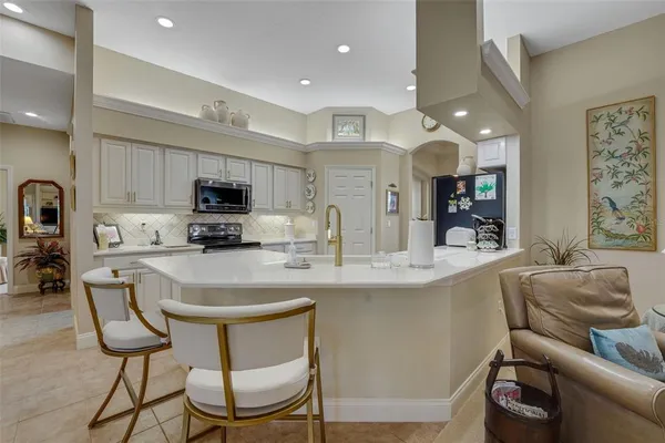 a kitchen with stainless steel appliances granite countertop a table chairs refrigerator and microwave