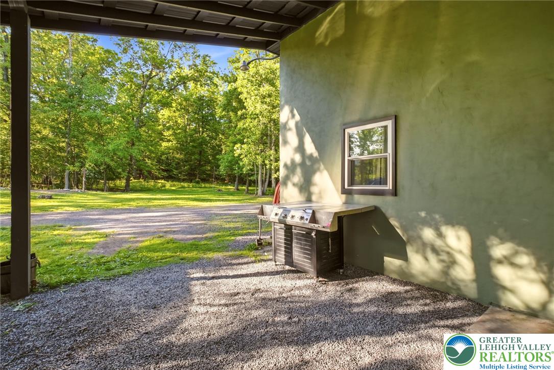 9033 Loop Road Slatington, PA 18080 - Photo 53 of 53 An inviting outdoor grilling area on a gravel patio, perfect for enjoying tranquil woodland views.