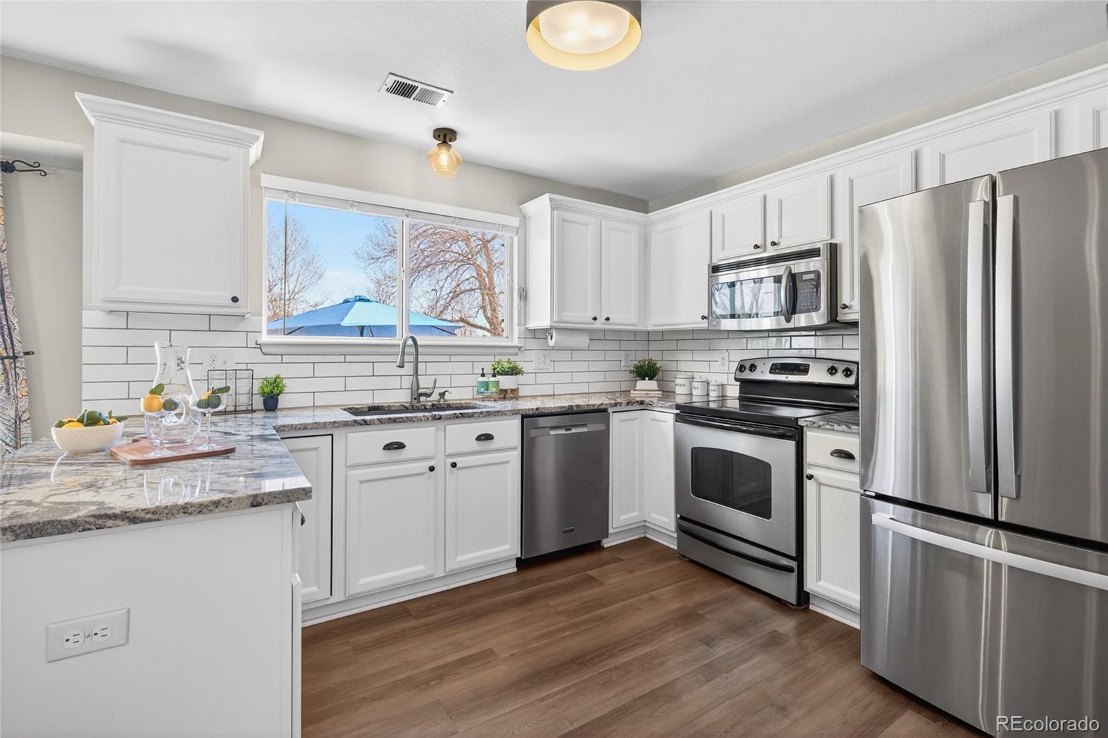 9600 South Castle Ridge Circle Highlands Ranch, CO 80129 - Photo 3 of 50 a kitchen with white cabinets sink and stainless steel appliances