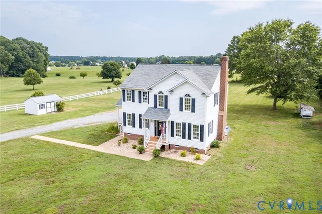 an aerial view of a house with swimming pool garden and tall trees