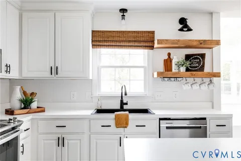 a kitchen with stainless steel appliances a stove and white cabinets