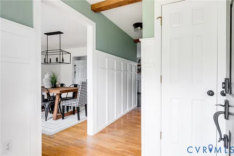 a view of a hallway with wooden floor and dining room view