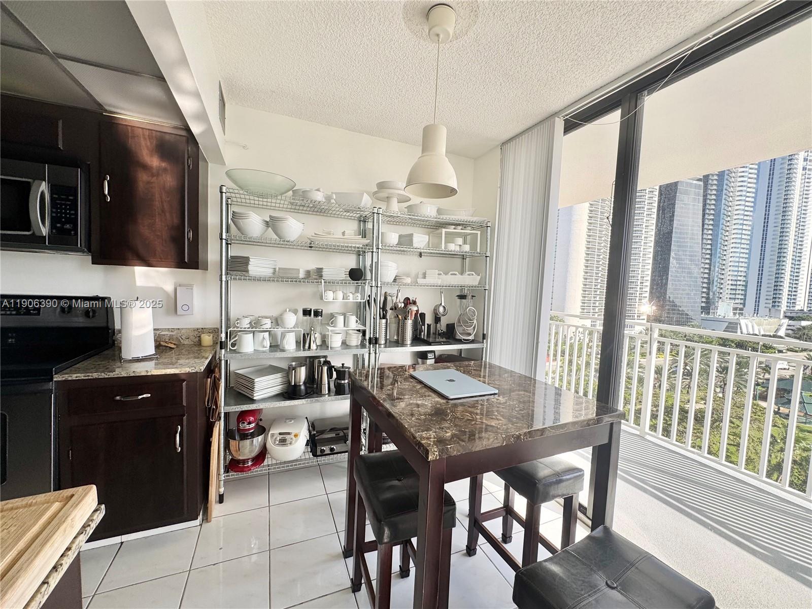 210 174th Street, Unit 1002 Sunny Isles Beach, FL 33160 - Photo 16 of 34 a kitchen with a table chairs and a stove