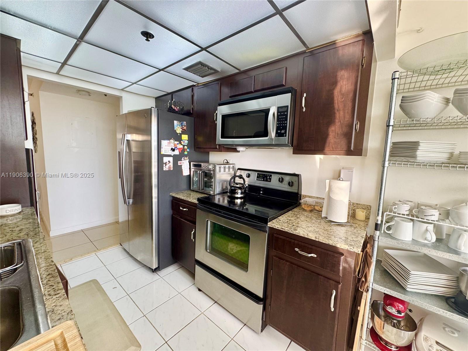 210 174th Street, Unit 1002 Sunny Isles Beach, FL 33160 - Photo 19 of 34 a kitchen with stainless steel appliances granite countertop a refrigerator and a stove top oven