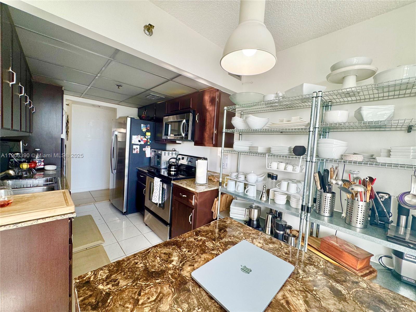 210 174th Street, Unit 1002 Sunny Isles Beach, FL 33160 - Photo 20 of 34 a kitchen with stainless steel appliances kitchen island granite countertop a sink refrigerator and cabinets