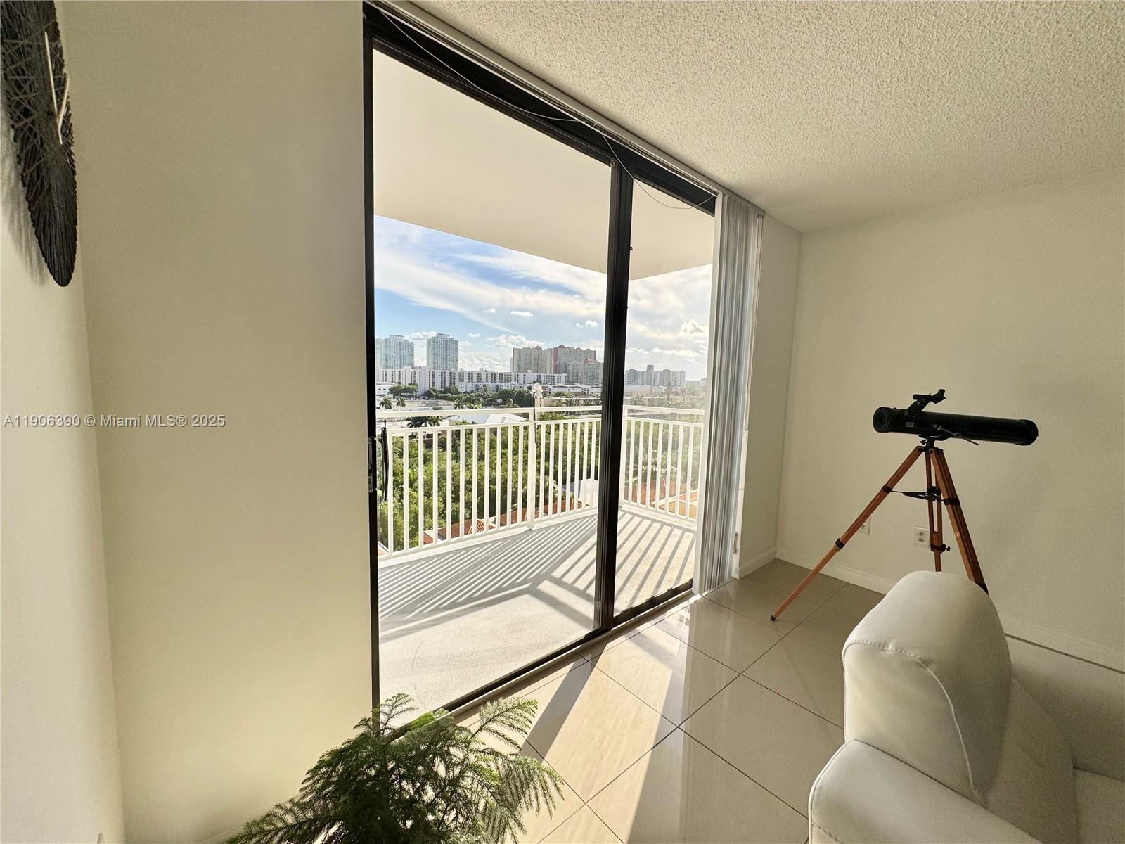 210 174th Street, Unit 1002 Sunny Isles Beach, FL 33160 - Photo 10 of 34 a living room with a floor to ceiling window and a flat screen tv