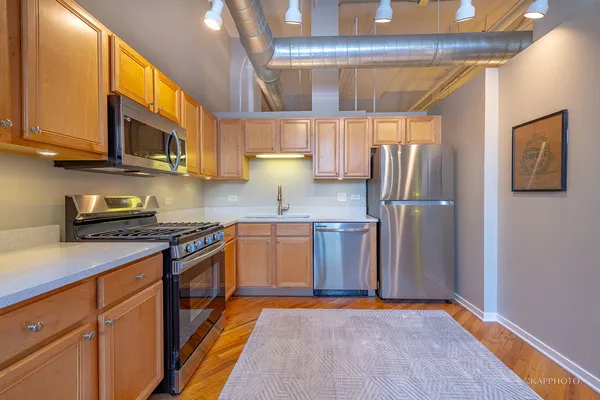 a kitchen with stainless steel appliances granite countertop a refrigerator a stove top oven a sink and dishwasher