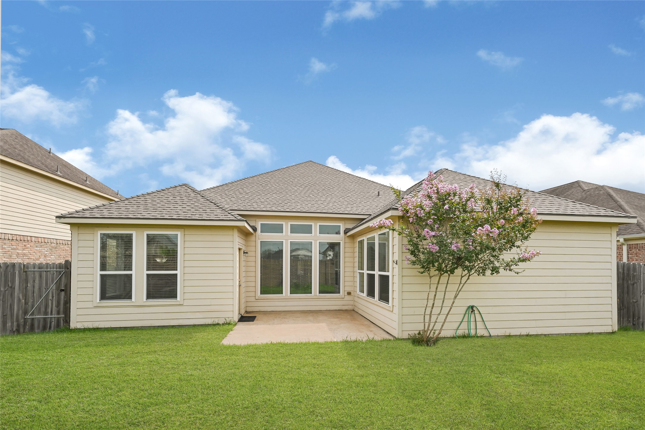 4702 Sedgewood Drive Rosenberg, TX 77471 - Photo 24 of 24 This home features a charming backyard with a well-maintained lawn, a small patio area, and a flowering tree, perfect for outdoor enjoyment and entertaining. The house has a light exterior and large windows that enhance natural light inside.