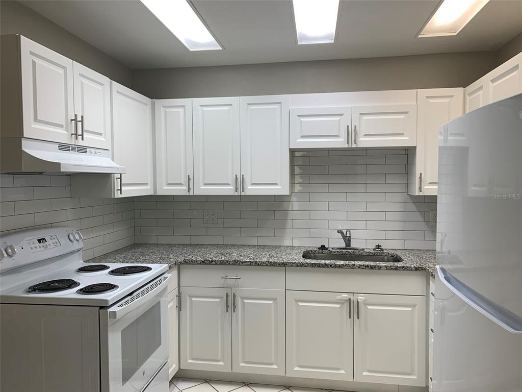 3756 Amherst Way, Unit 1 Sarasota, FL 34232 - Photo 3 of 14 a kitchen with granite countertop white cabinets and white appliances