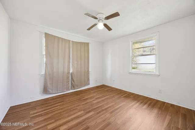a view of empty room with wooden floor and fan