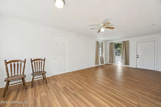 a view of an empty room with a window and wooden floor