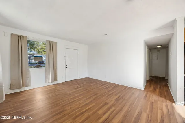 a view of a room with wooden floor and a window