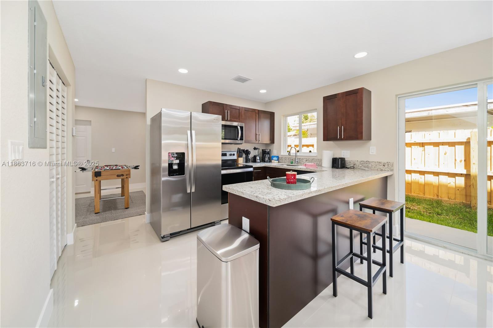 1183 Northeast 111th Street, Unit 1183 Miami, FL 33161 - Photo 6 of 20 a kitchen with stainless steel appliances granite countertop a sink a stove a refrigerator cabinets and a dining table with wooden floor