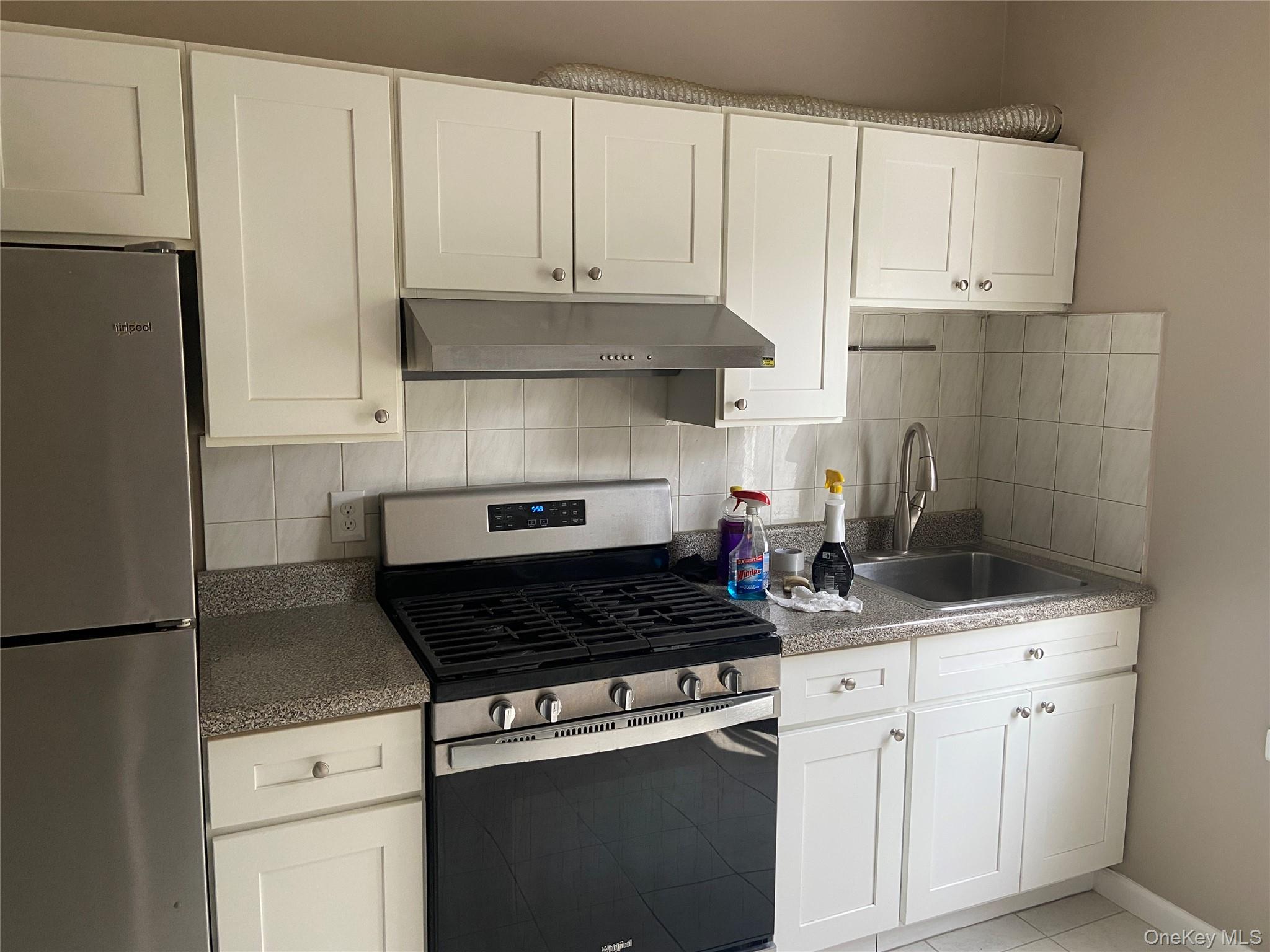 Kitchen featuring white shaker-style cabinetry, a stainless steel gas range with a matching range hood, and a stainless steel refrigerator