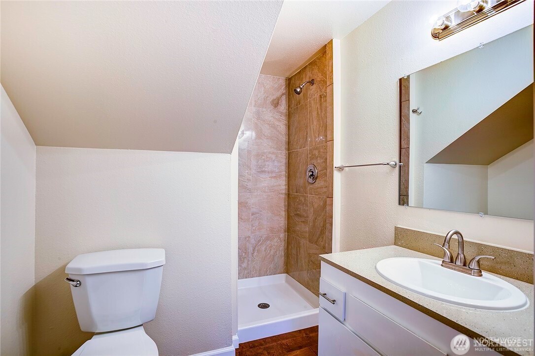 2357 Northwest 65th Street Seattle, WA 98117 - Photo 17 of 20 a bathroom with a sink a toilet a mirror and shower