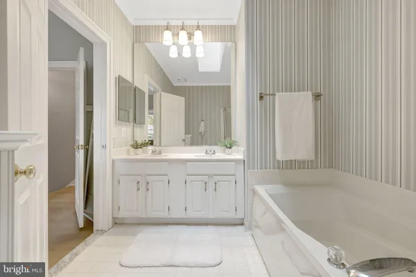 a bathroom with a tub a sink and a large mirror