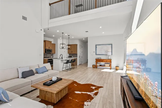 a living room with furniture kitchen view and a wooden floor