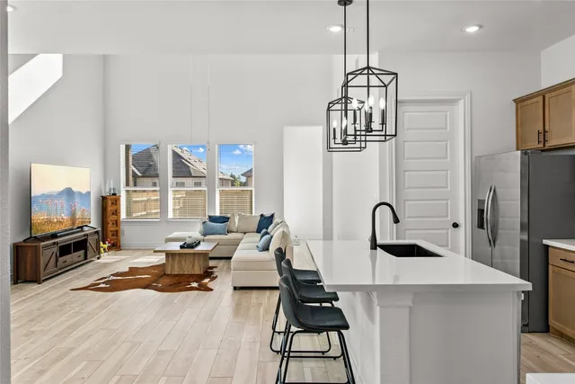 a living room with furniture a flat screen tv and a refrigerator