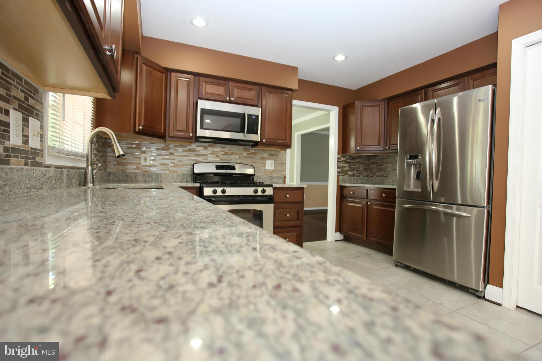 703 Monarch Ridge Road Frederick, MD 21703 - Photo 2 of 30 a kitchen with granite countertop a refrigerator a sink a stove and cabinets