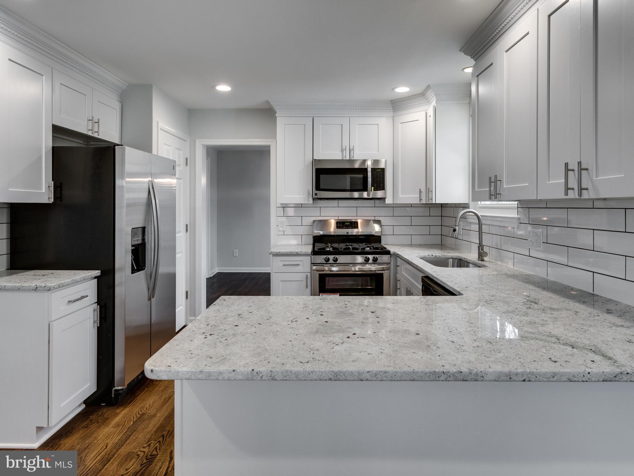 8918 Victoria Road Springfield, VA 22151 - Photo 6 of 30 a kitchen with stainless steel appliances granite countertop a sink a stove a refrigerator a microwave and cabinets