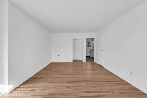 a view of an empty room with wooden floor and closet