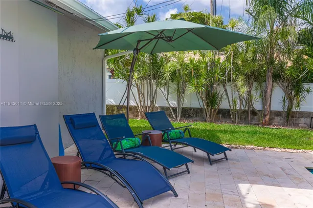 a backyard of a house with table and chairs under an umbrella