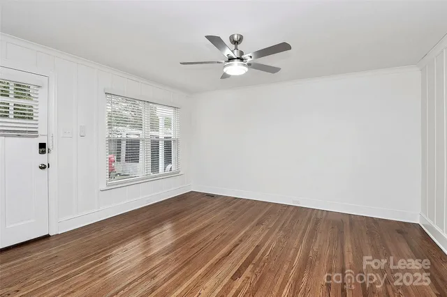 a view of an empty room with wooden floor and a window