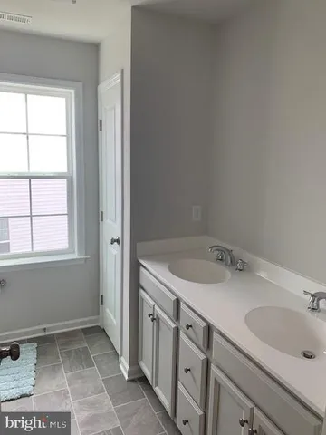 a bathroom with a granite countertop sink a toilet and a window