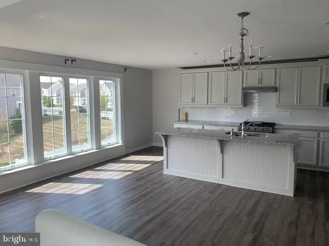a kitchen with stainless steel appliances granite countertop a sink a stove and white cabinets next to a window