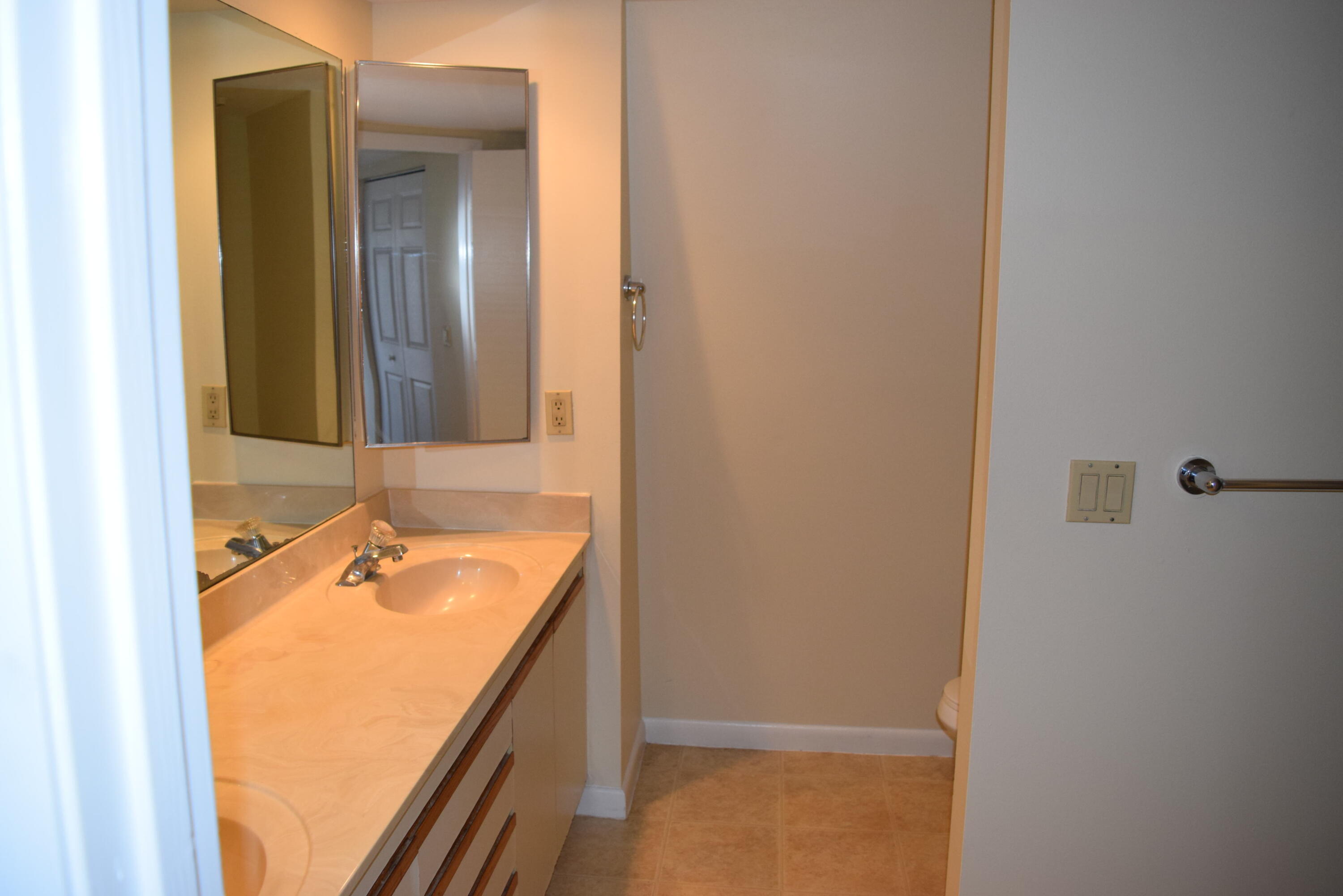 5945 Southeast Windsong Lane, Unit 907 Stuart, FL 34997 - Photo 14 of 34 a bathroom with a granite countertop sink and a mirror