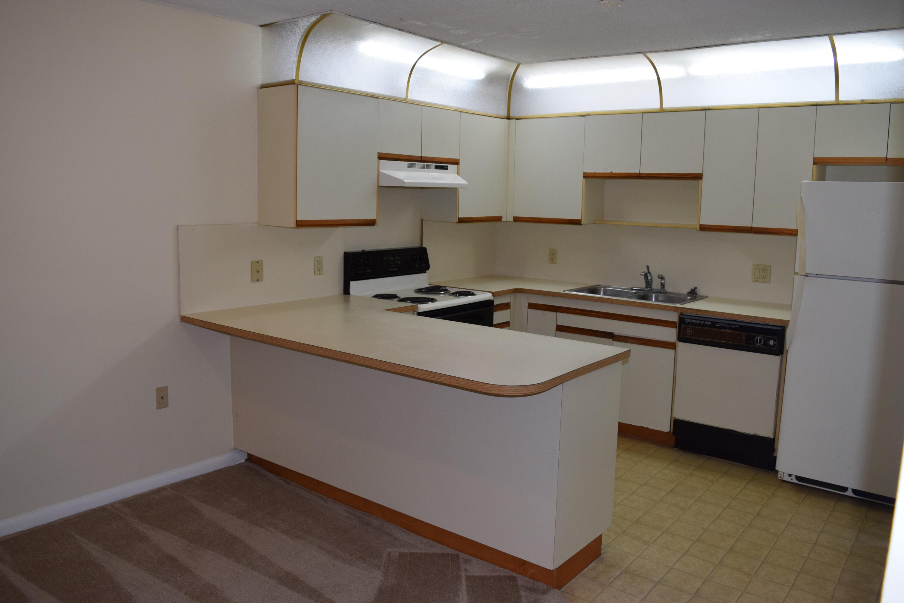 5945 Southeast Windsong Lane, Unit 907 Stuart, FL 34997 - Photo 6 of 34 a kitchen that has a sink a stove and a refrigerator