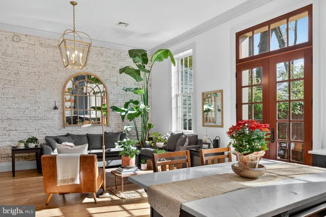 a living room with couches chandelier and a dining table with garden view