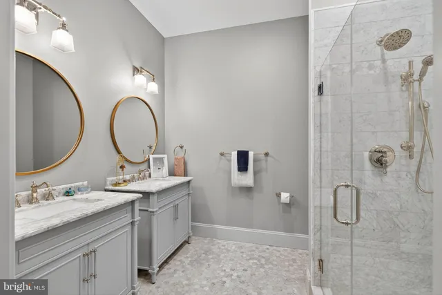 a bathroom with a granite countertop double vanity sink mirror and shower
