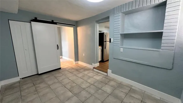 a view of a refrigerator in kitchen and an empty room