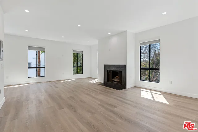 an empty room with windows and fireplace