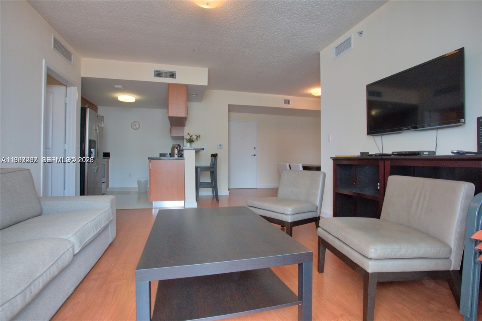601 Northeast 23rd Street, Unit 1004 Miami, FL 33137 - Photo 4 of 17 a living room with furniture and a flat screen tv