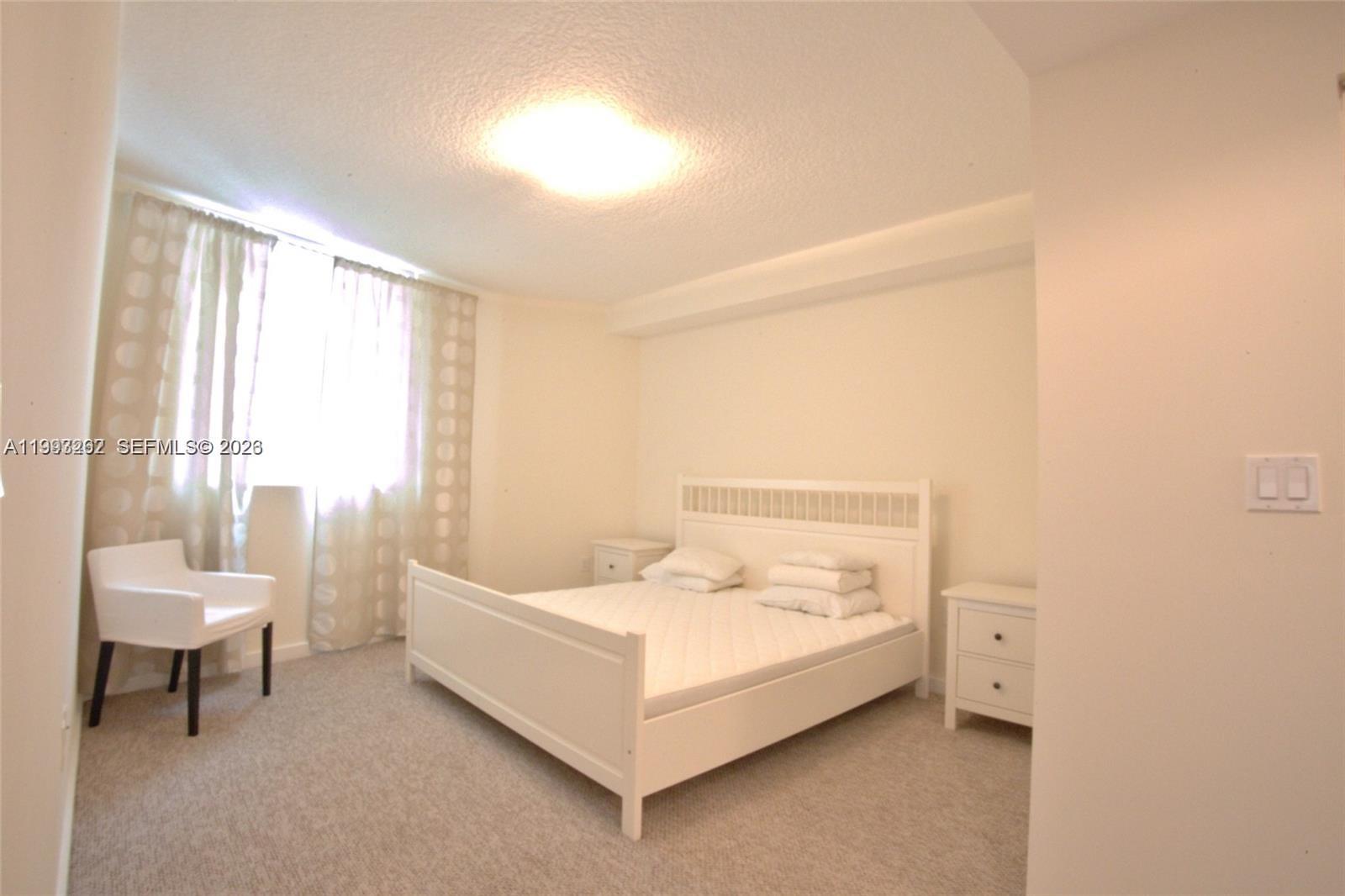 601 Northeast 23rd Street, Unit 1004 Miami, FL 33137 - Photo 8 of 17 a spacious bedroom with a bed and a chair