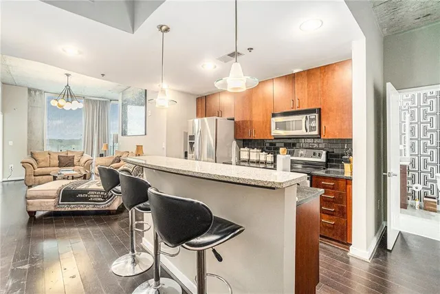 a kitchen with stainless steel appliances kitchen island granite countertop a stove a sink a dining table and chairs with wooden floor