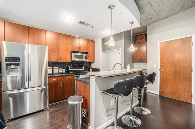 a kitchen with stainless steel appliances granite countertop a sink a stove a refrigerator cabinets and wooden floor