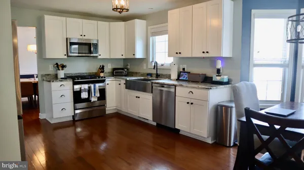 a kitchen with stainless steel appliances granite countertop a dining table chairs and a refrigerator