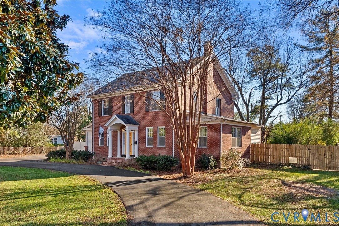 a view of a big yard in front of a brick house with large windows