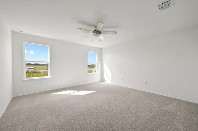 an empty room with windows and ceiling fan view