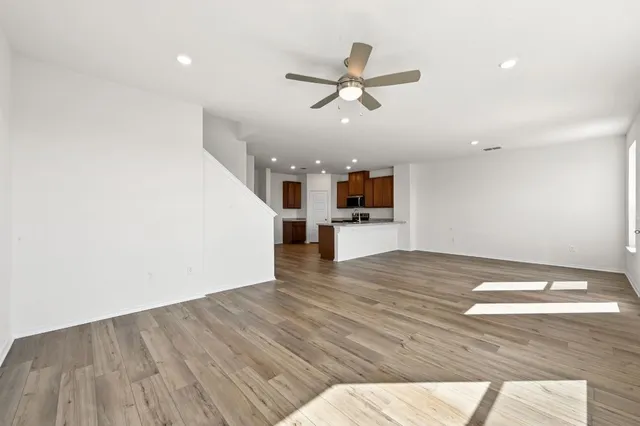 a view of empty room with wooden floor and ceiling fan
