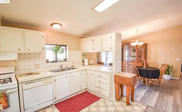 a kitchen with a sink stove and white cabinets with wooden floor