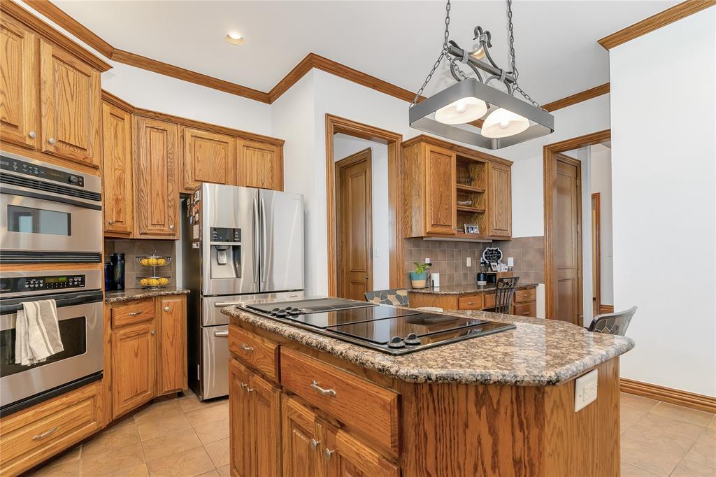 4520 South Nolan River Road Cleburne, TX 76033 - Photo 13 of 40 Kitchen featuring open shelves, brown cabinets, appliances with stainless steel finishes, and a kitchen island