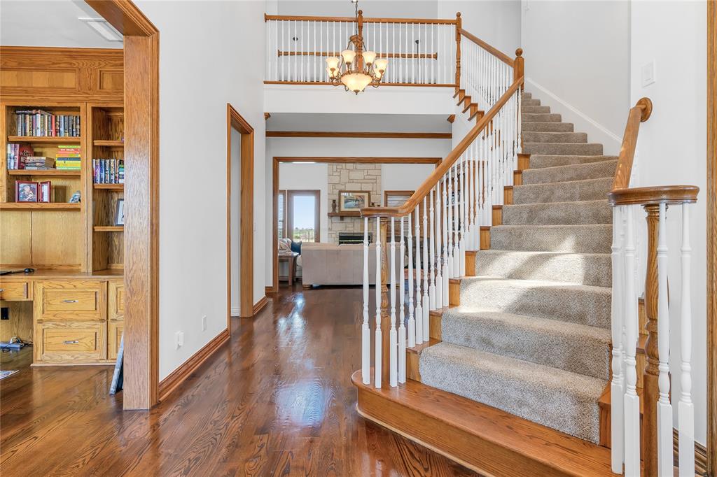 4520 South Nolan River Road Cleburne, TX 76033 - Photo 22 of 40 Foyer entrance featuring wood finished floors, a chandelier, baseboards, a towering ceiling, and stairs