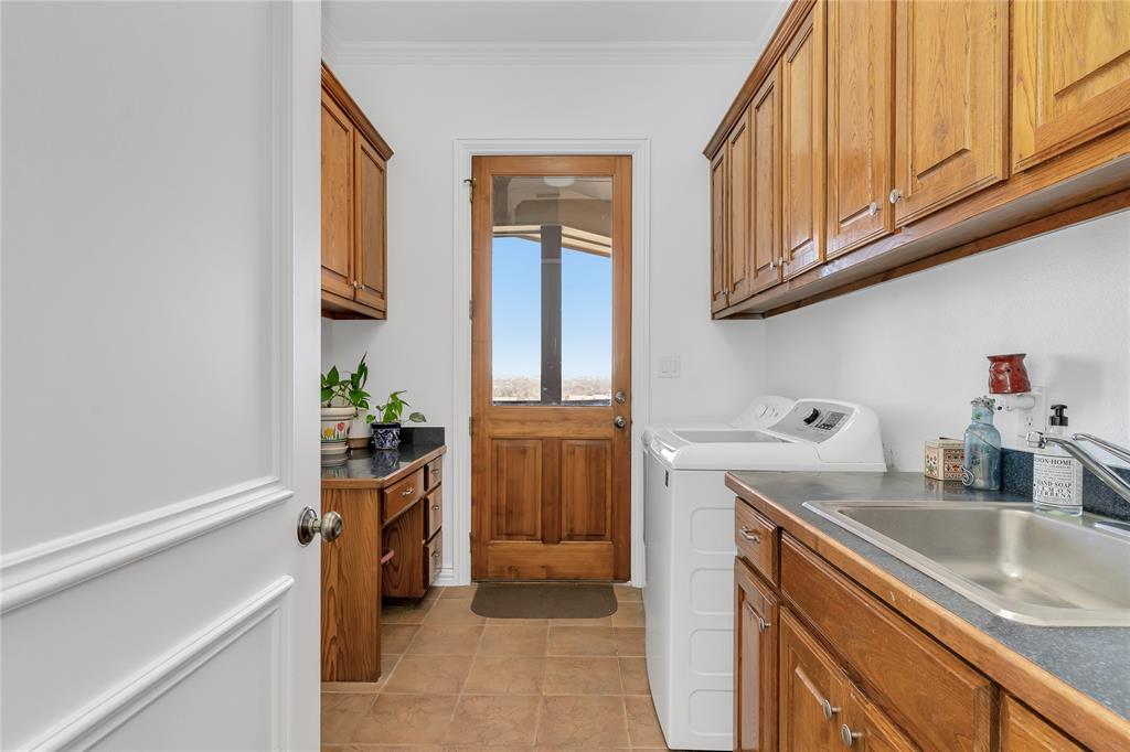 4520 South Nolan River Road Cleburne, TX 76033 - Photo 26 of 40 Washroom with crown molding, light tile patterned floors, washer and dryer, cabinet space, and a sink