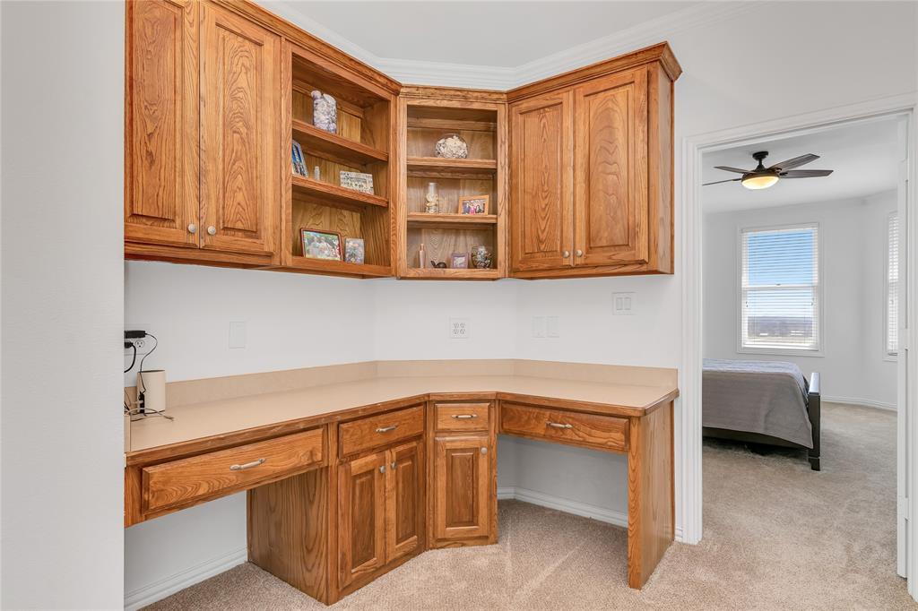 4520 South Nolan River Road Cleburne, TX 76033 - Photo 31 of 40 Kitchen featuring brown cabinets, built in desk, and light carpet